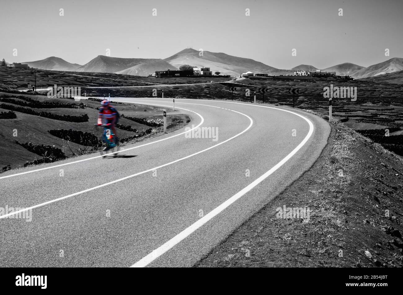 Un ciclista che si gode la strada aperta e il paesaggio vario e robusto di Lanzarote. Foto Stock