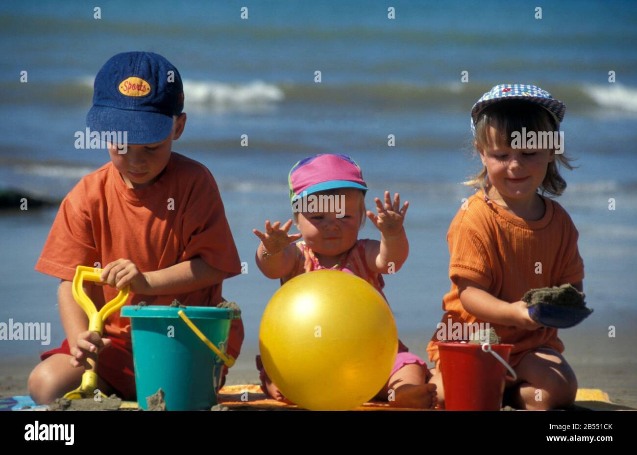 baby e fratelli che giocano con secchi e picche sulla spiaggia Foto Stock