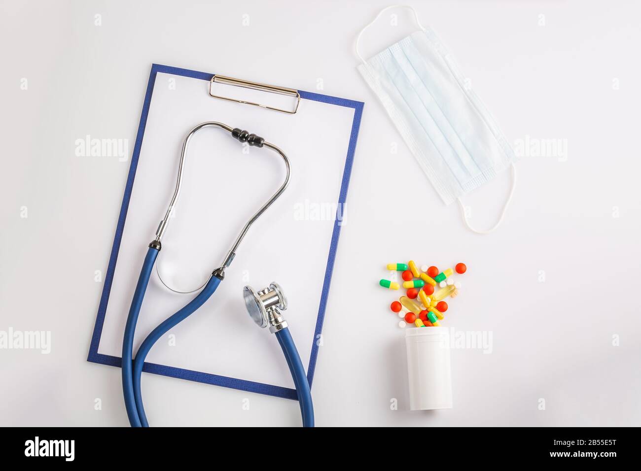 Stetoscopio, appunti, maschera e pillole colorate dalla bottiglia su sfondo bianco isolato su bianco. Concetto di virus 2019-nCoV, coronavirus, illne Foto Stock