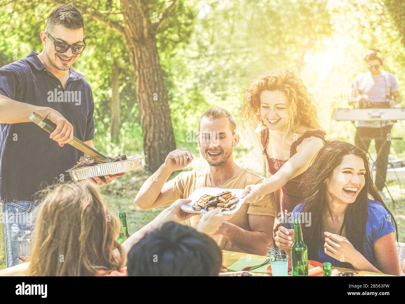 Amici felici divertirsi a festa barbecue bere birra, mangiare, ascoltare musica - giovani godendo barbecue cena all'aperto - amicizia e estate c Foto Stock