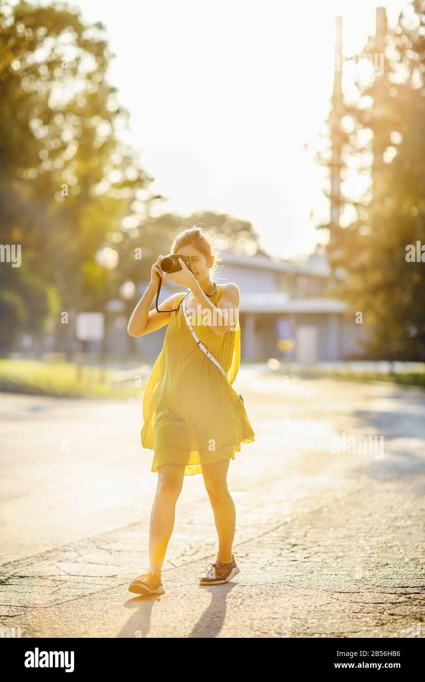 Giovane donna con macchina fotografica che cammina nel parco Foto Stock