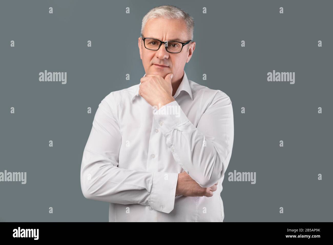 Ritratto dell'uomo pensivo anziano su sfondo grigio Foto Stock