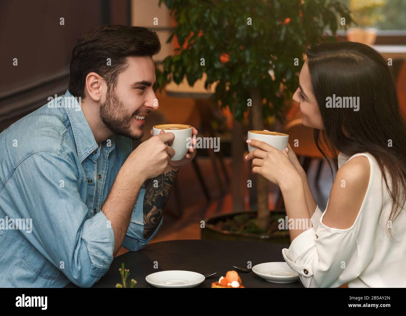 Il Ragazzo E La Ragazza Si Godono Il Caffè Seduti Al Cafe Table Indoor Foto Stock