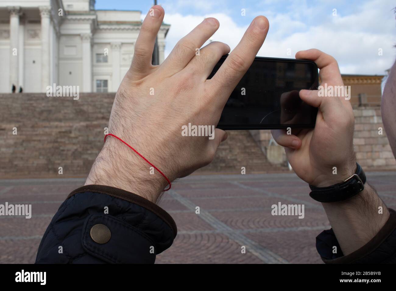 Il turista scatta una foto sul suo primo piano del telefono. Smartphone in mano con sfondo esterno. Display nero Foto Stock