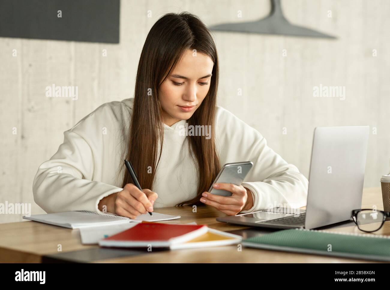 Freelance scrivere in notebook e guardare lo smartphone Foto Stock