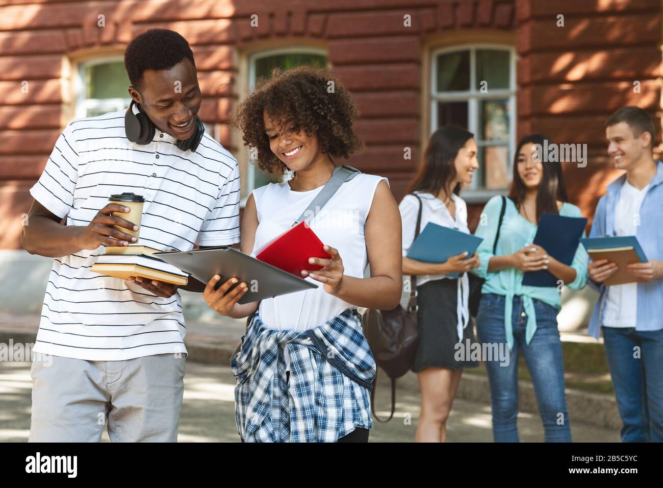 Coppia Di Studenti Afroamericani In Piedi All'Aperto Lezioni Di Lettura Programmare Insieme Foto Stock