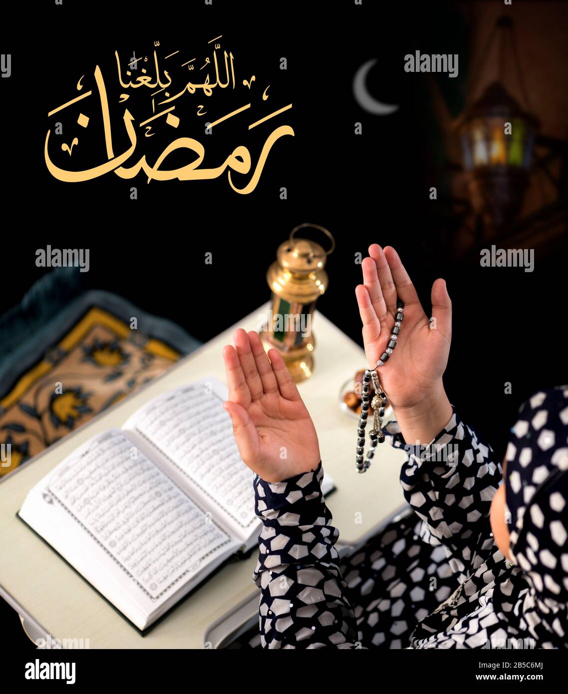Ragazza musulmana Che Alza Le Mani per la preghiera su sfondo nero, con il testo arabo di Calligraphy Che Dice 'Dio, aiutaci a raggiungere il Ramadan' Foto Stock