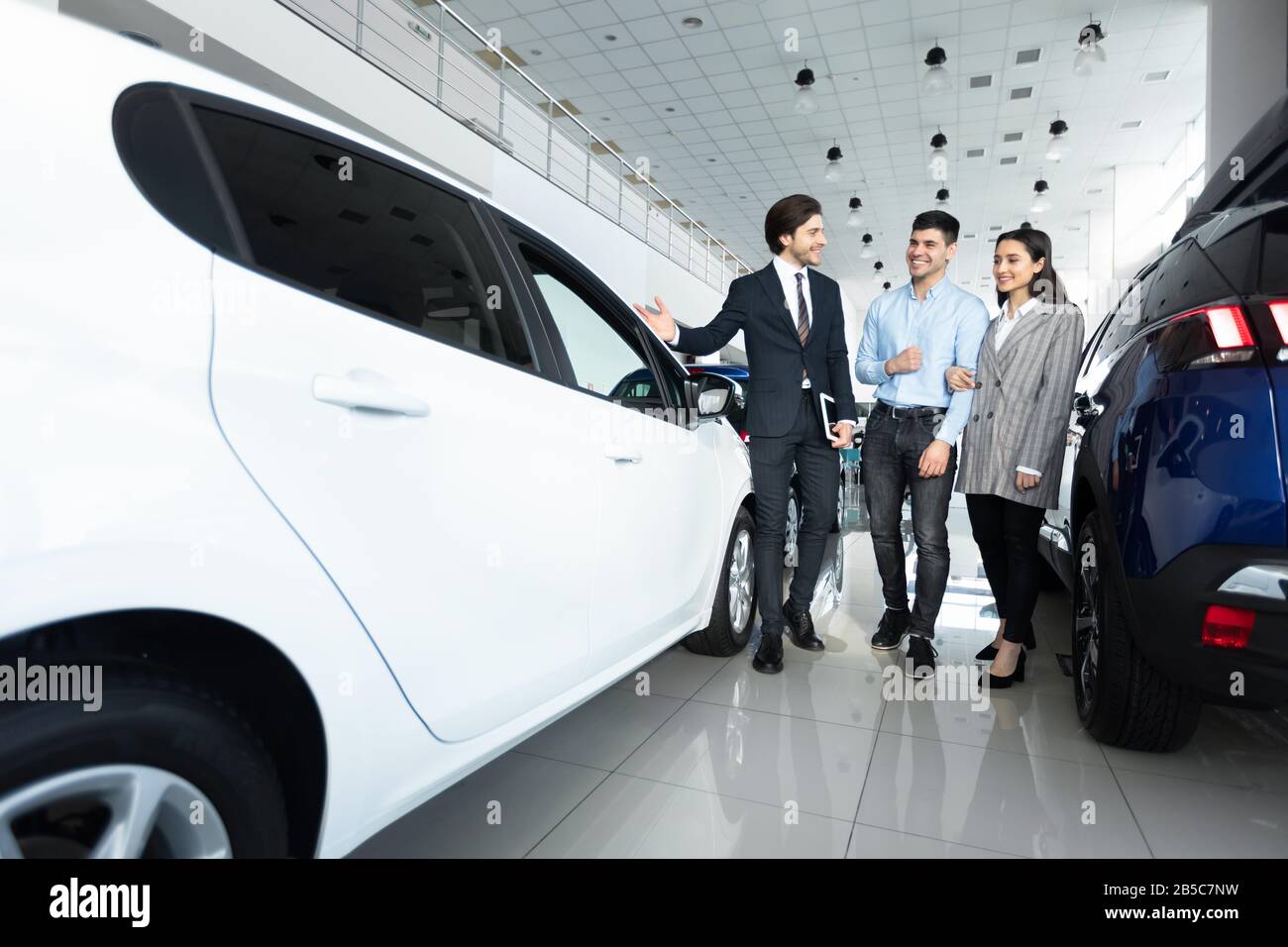 Responsabile Vendite Auto Che Mostra Auto Agli Acquirenti Presso Il Dealership Store Foto Stock