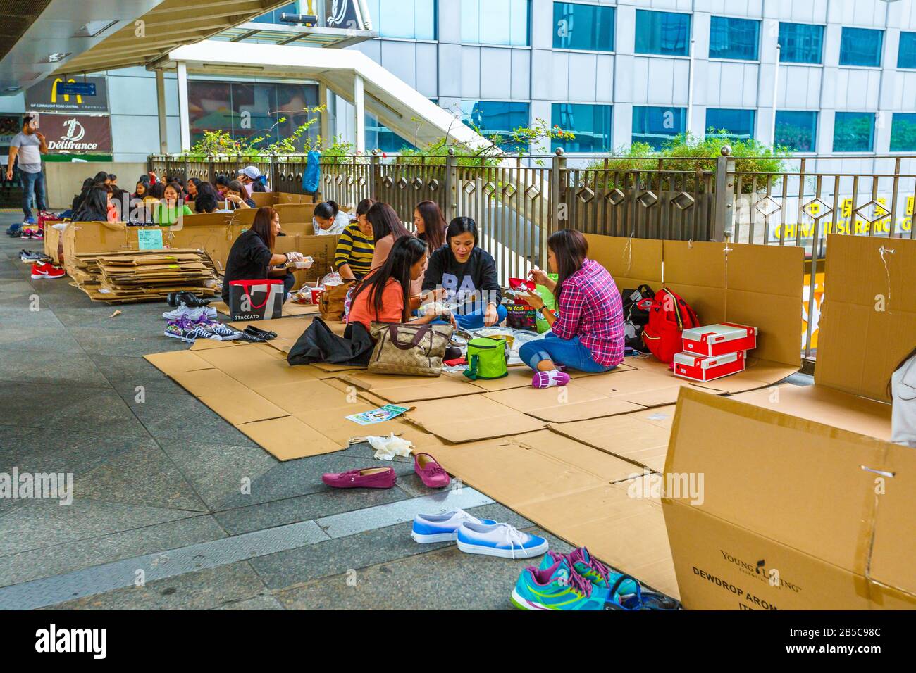 Hong Kong, Cina - 4 dicembre 2016: Donne asiatiche che riposano e pranzano sotto il portico del centro commerciale IFC Mall. Il quartiere centrale di Foto Stock