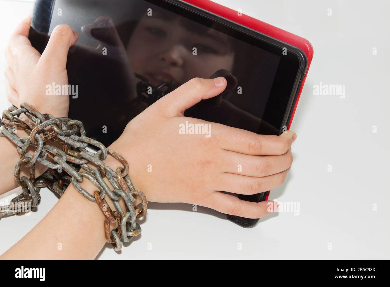 La catena di ferro unisce le mani e lo smartphone - concetto di dipendenza del telefono cellulare. Foto Stock