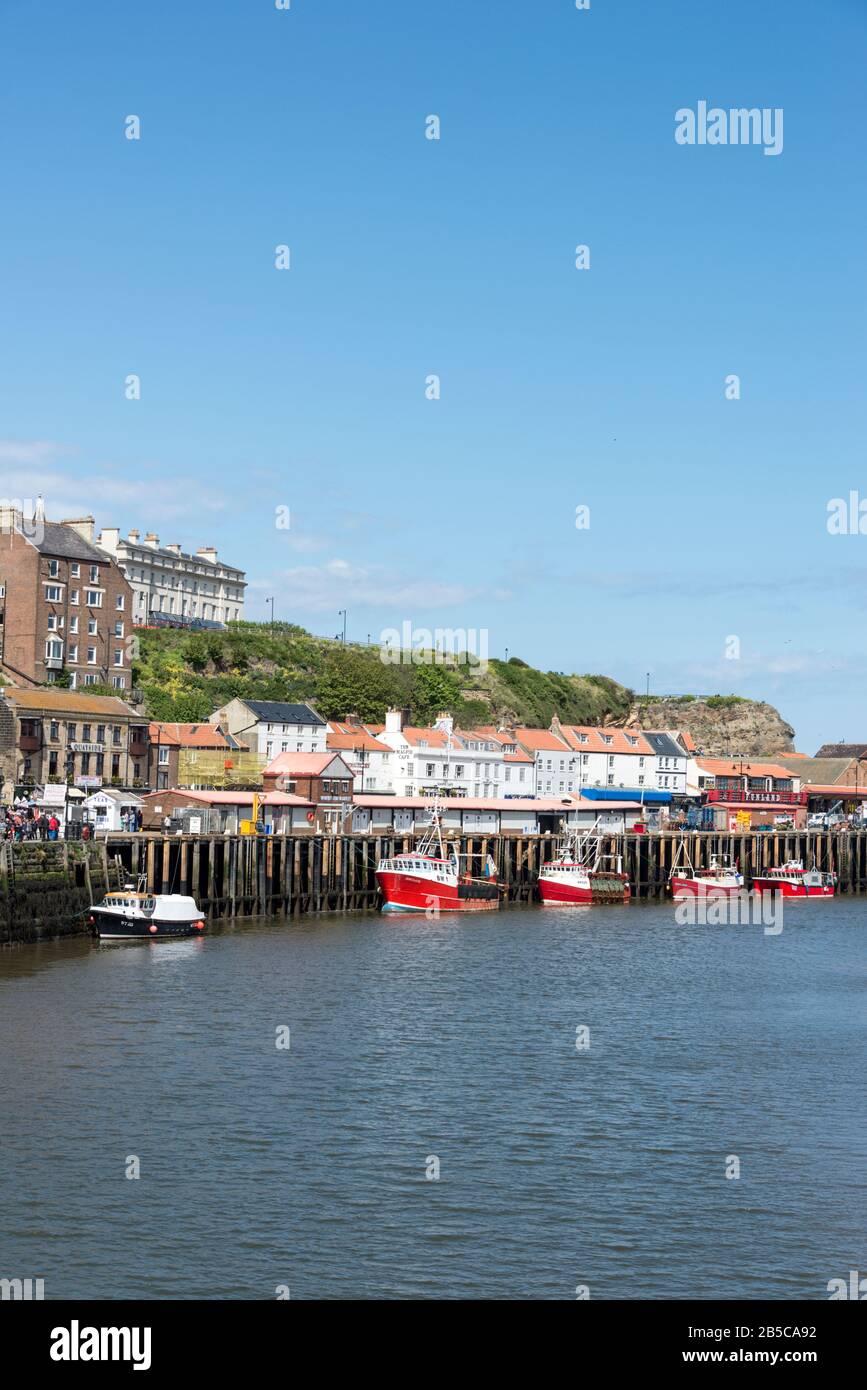 Una piccola flotta di pescherecci con reti da traino da pesca rosse ormeggiati sul fiume Esk al porto di pescatori di Whitby nel North Yorkshire, la Gran Bretagna Whitby, una città balneare e un piccolo accesso wi-fi Foto Stock