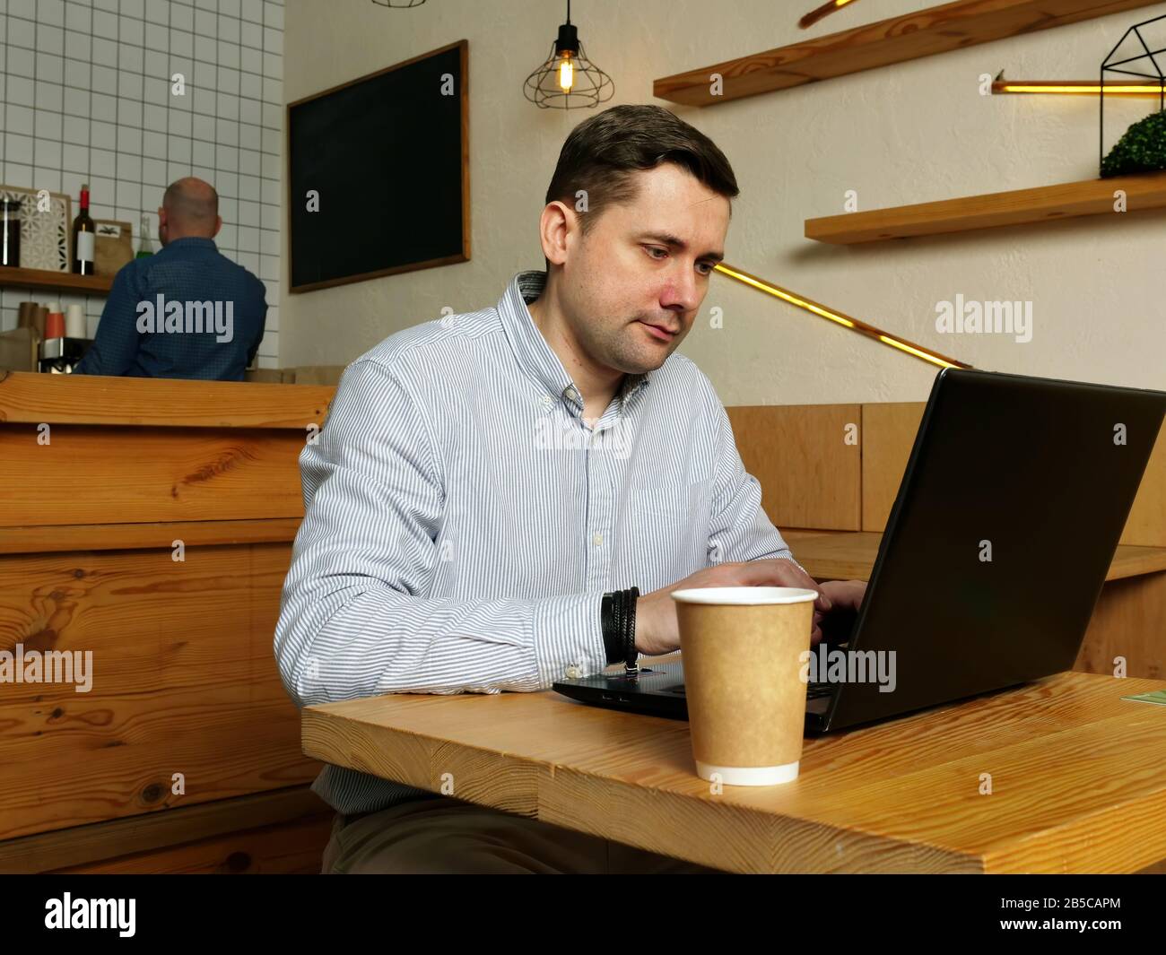 L'uomo sta digitando su un computer portatile nel caffè. Foto Stock