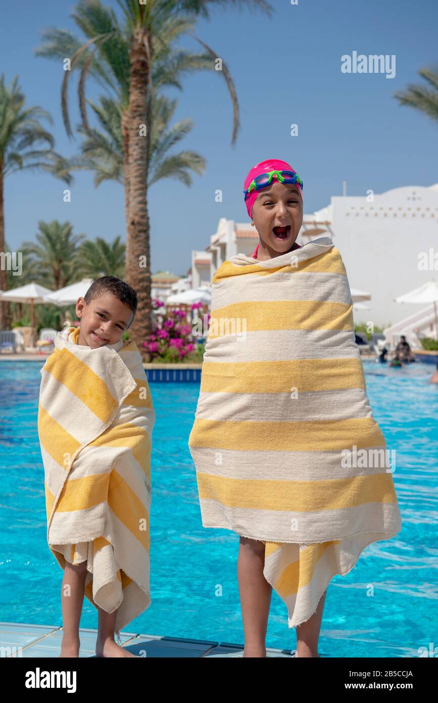 Happy Young Boy e Girl Coperte di asciugamani in piscina Foto Stock
