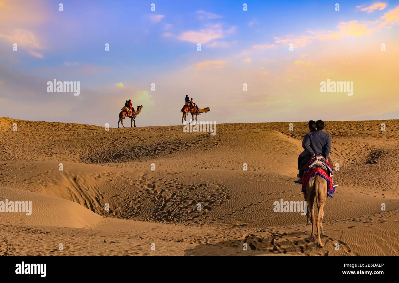 Coppia turistica godere di un safari del cammello al tramonto al deserto di Thar Jaisalmer Rajasthan, India Foto Stock