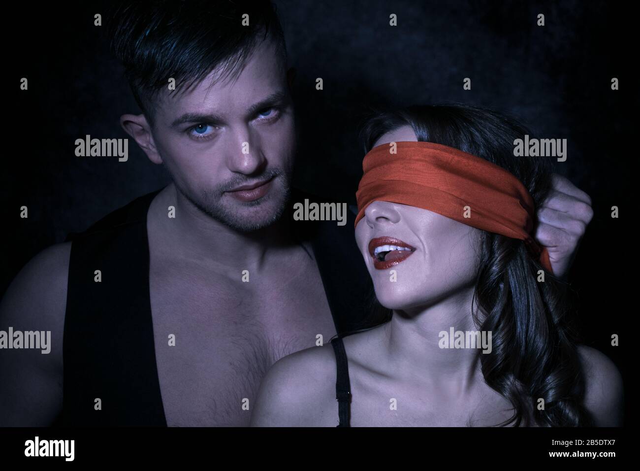 Ritratto sexy di coppia maschile e femminile con uomo che guarda la macchina  fotografica come donna indossa bending rosso e lecca le labbra Foto stock -  Alamy