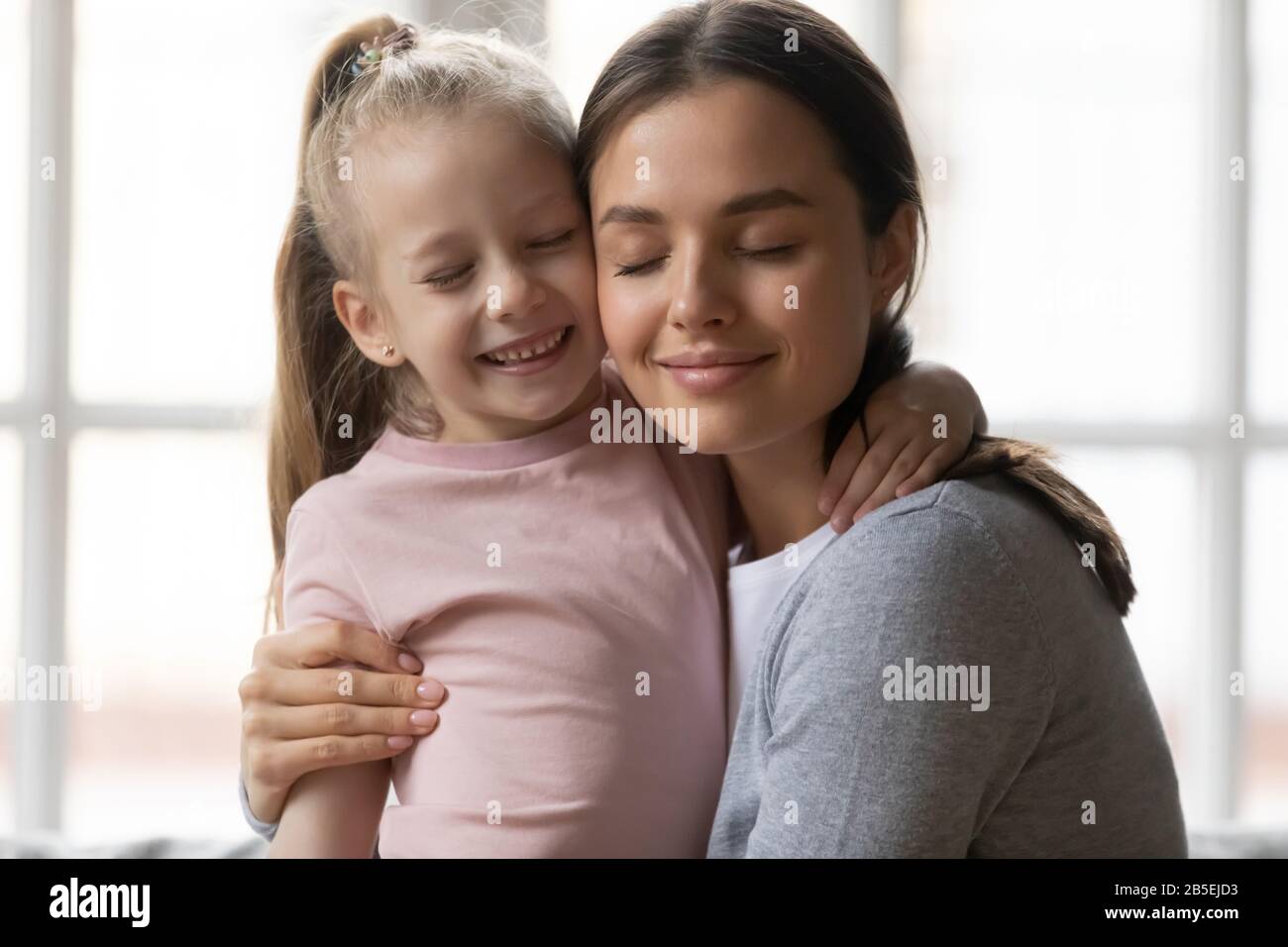 Amando piccola ragazza del capretto che abbraccia la nanny della babysitter della sorella maggiore. Foto Stock
