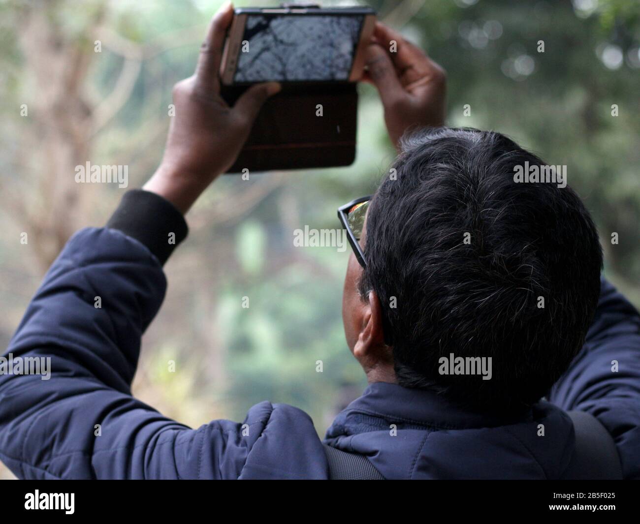 Un uomo che scatta foto con il cellulare allo zoo di kolkata. Foto Stock