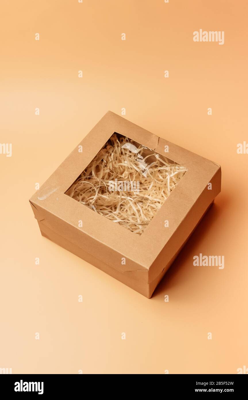 scatola regalo artigianale all'interno con fieno di carta su sfondo beige, isolato. Copyspace. Il concetto di vendite, sconti, regali di Natale e shopping. Foto Stock