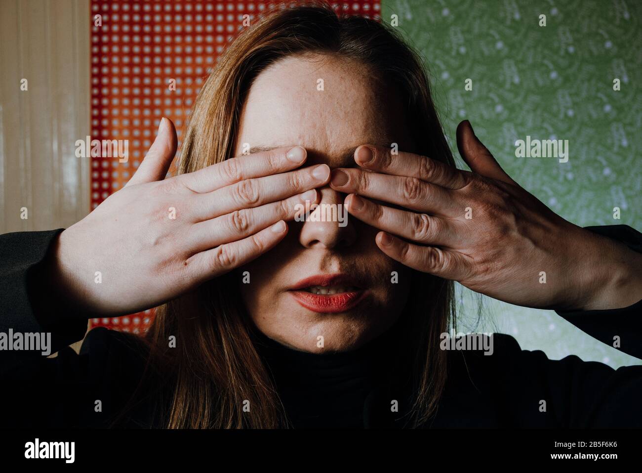 donna spaventata coprire i suoi occhi con mani impaurite e abusate nascondere Foto Stock