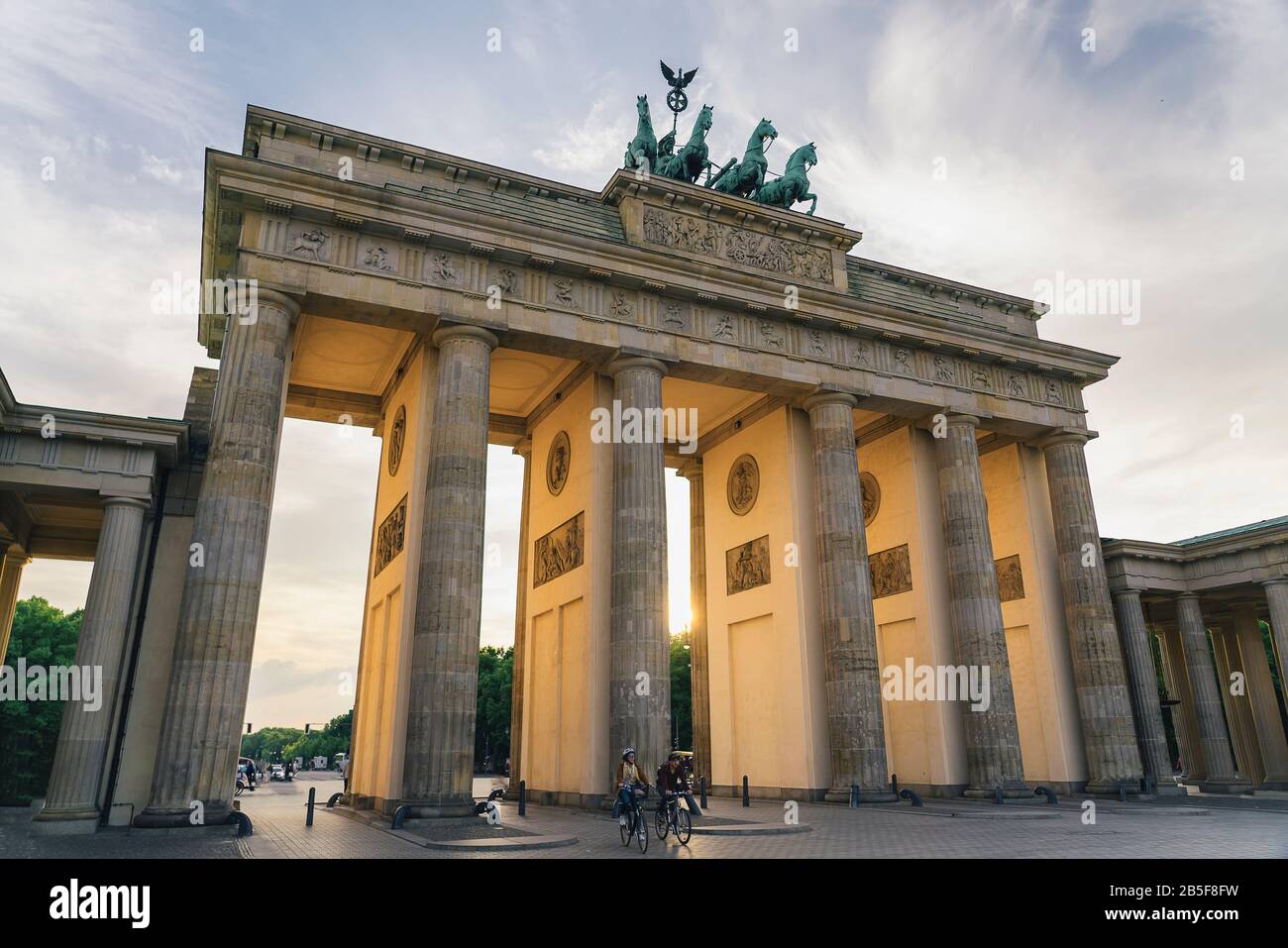 Due ciclisti alla porta di Brandeburgo al tramonto, Berlino, Germania Foto Stock