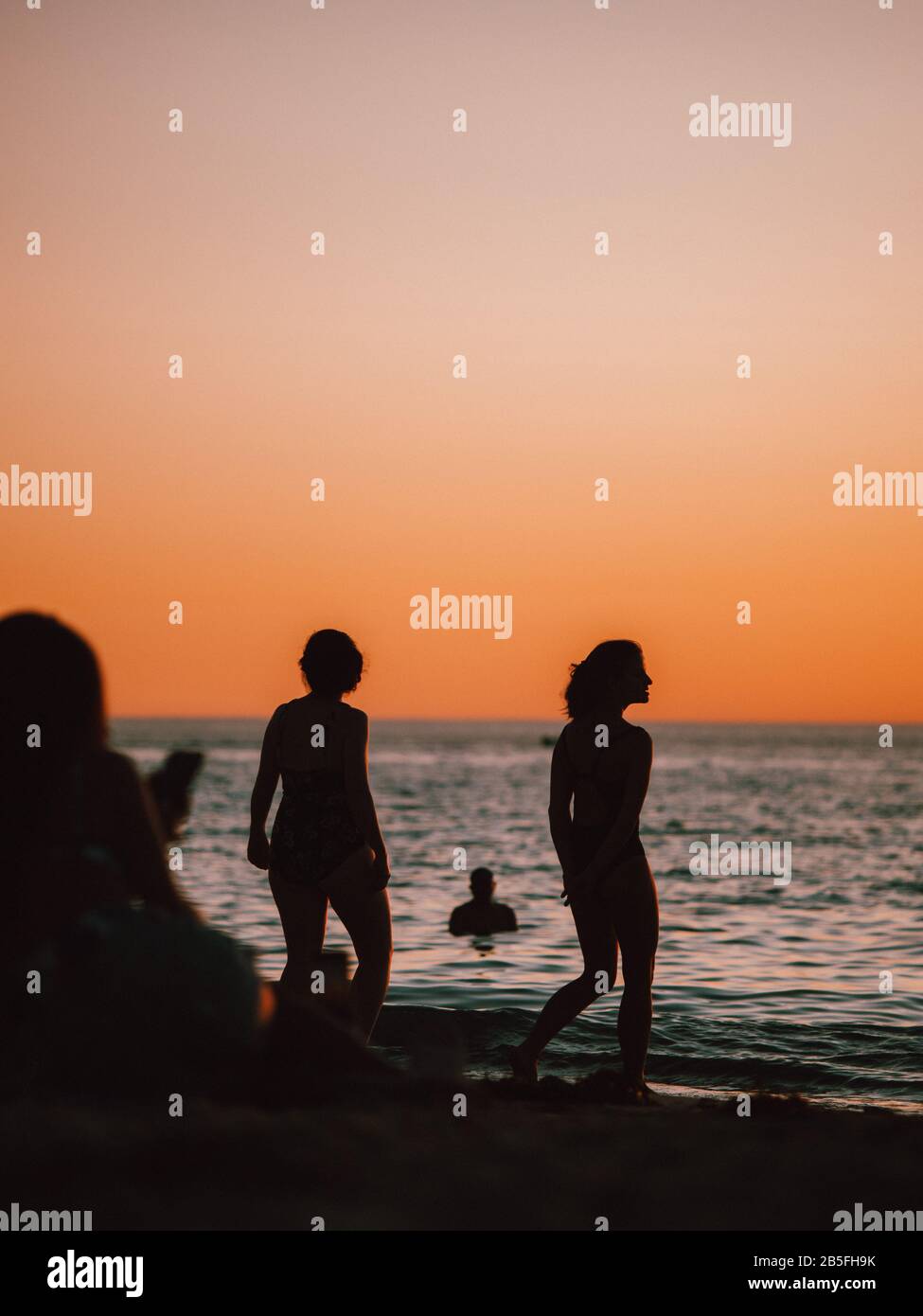 Alcune sagome di persone si sono riunite sulla riva di a. spiaggia al tramonto in Australia Foto Stock
