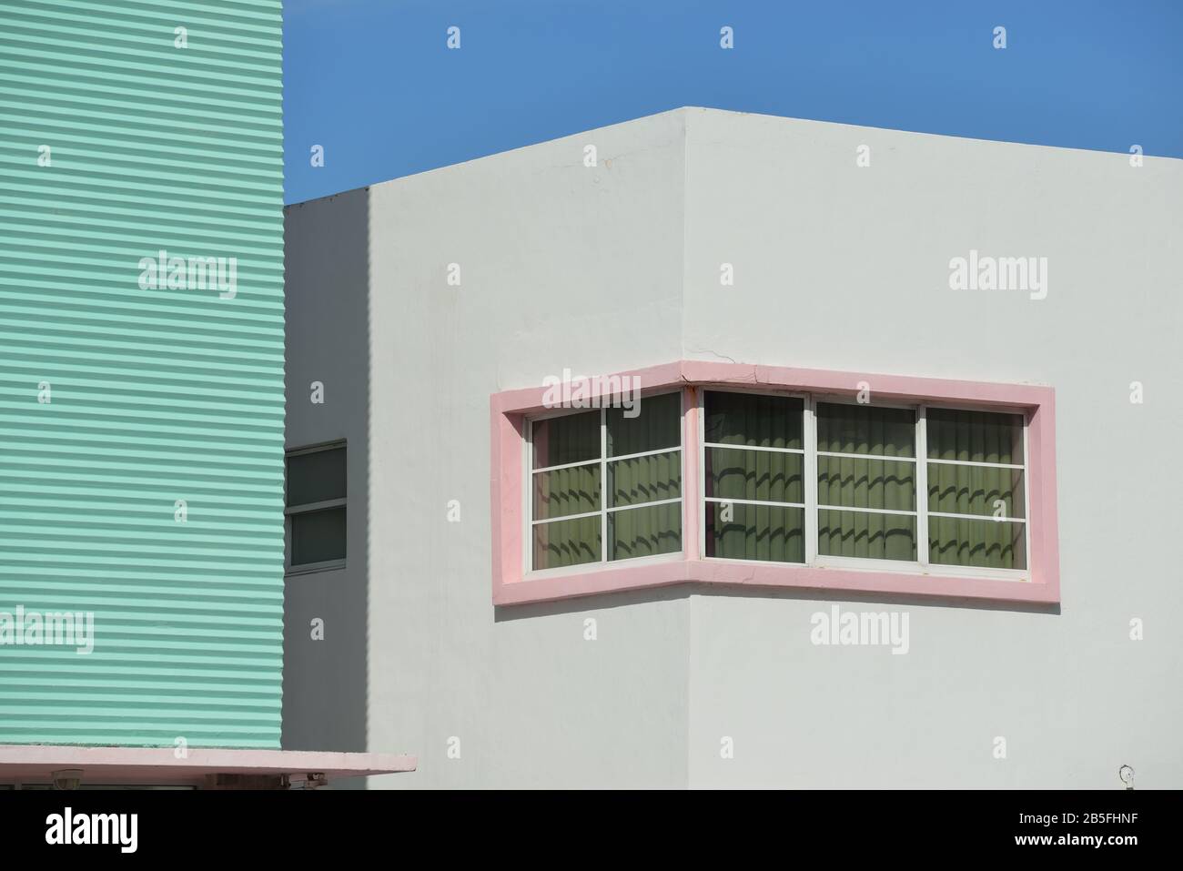 Pareti e finestre Art Deco sulle facciate dell'edificio di South Beach. Telai in cemento rosa, superfici ondulate e forme geometriche contro il cielo azzurro. Arch Foto Stock