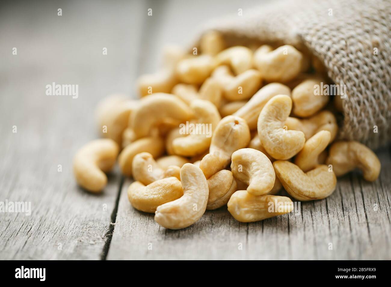 Cashew noci in sacco a sacco su sfondo di legno . Cibo sano. Noce indiano, Anacardio occidentale Foto Stock