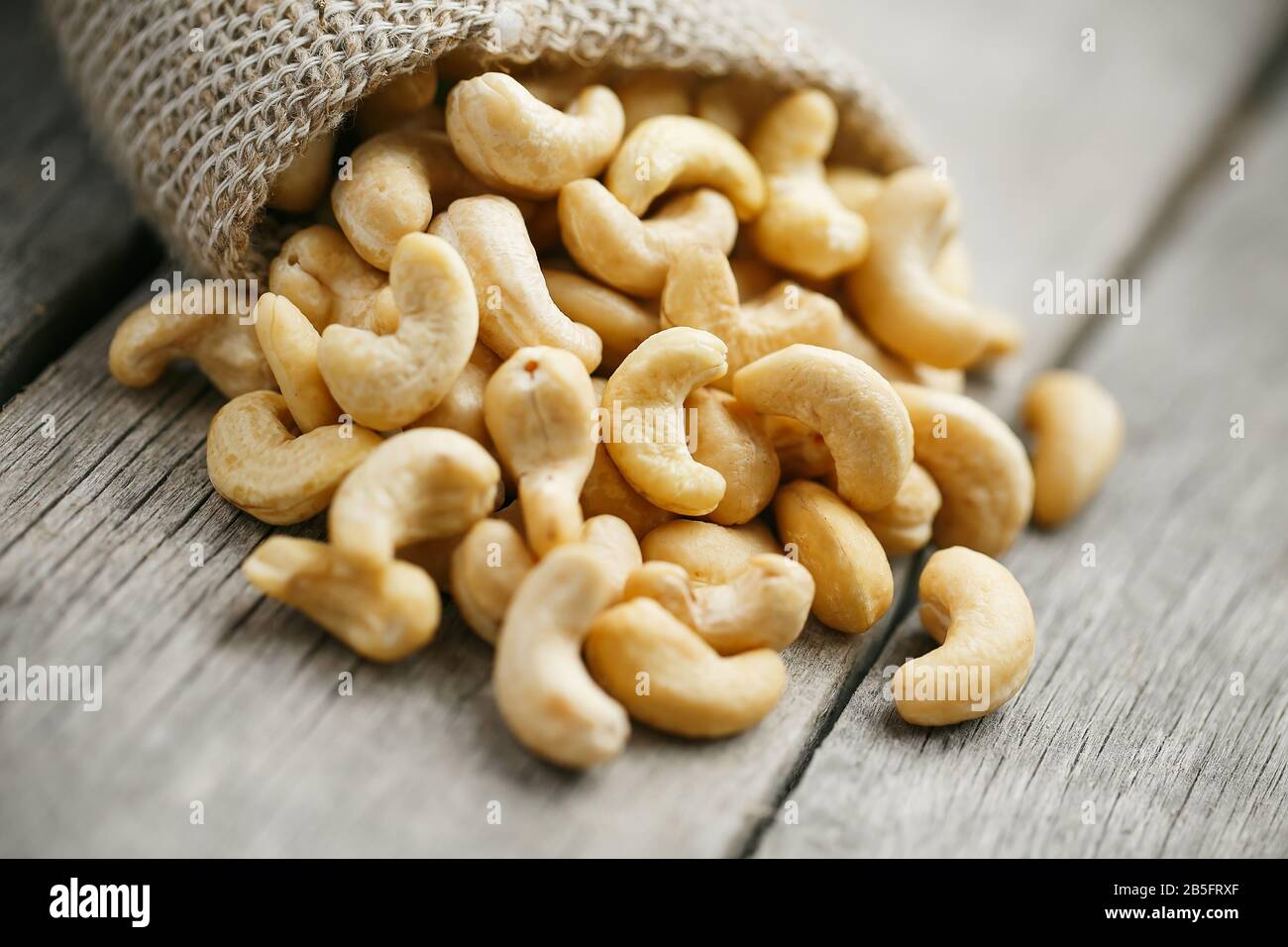 Cashew noci in sacco a sacco su sfondo di legno . Cibo sano. Noce indiano, Anacardio occidentale Foto Stock