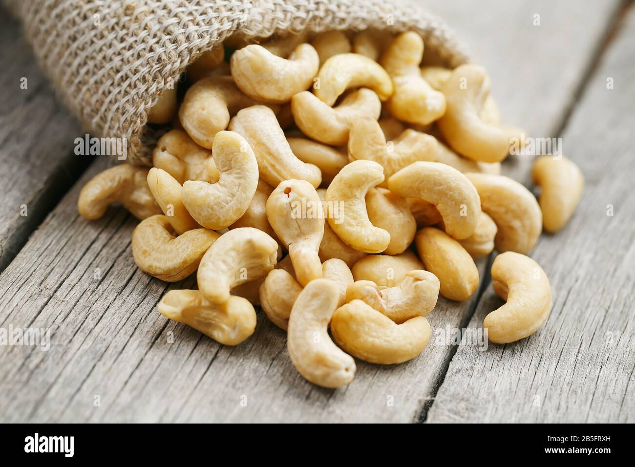 Cashew noci in sacco a sacco su sfondo di legno . Cibo sano. Noce indiano, Anacardio occidentale Foto Stock