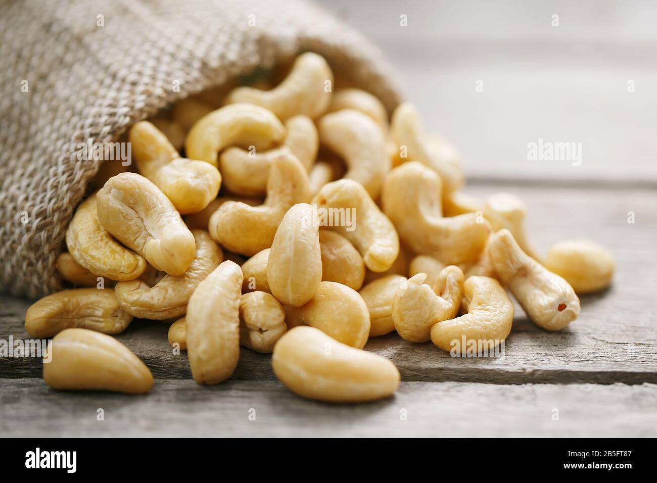 Cashew noci in sacco a sacco su sfondo di legno . Cibo sano. Noce indiano, Anacardio occidentale Foto Stock