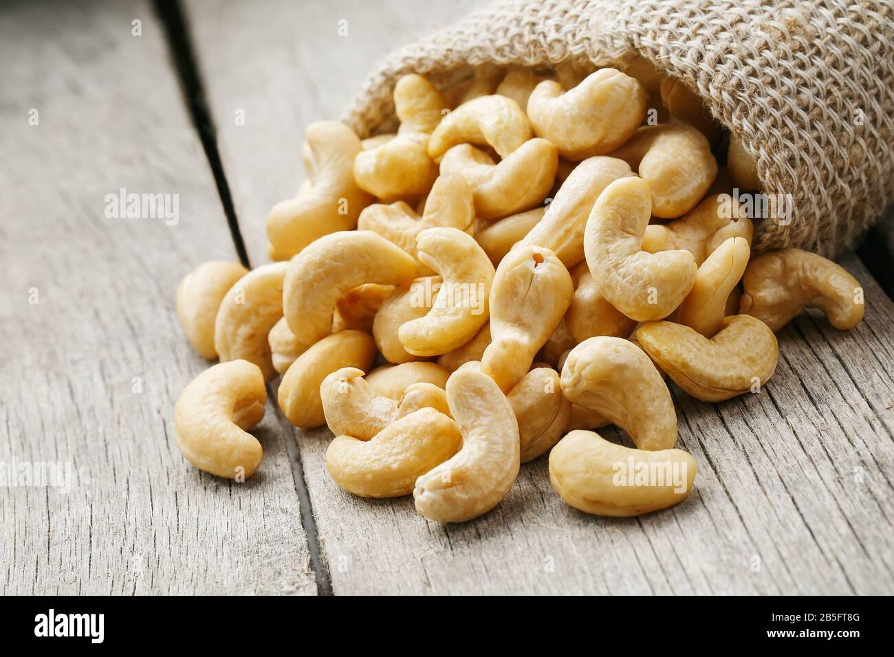 Cashew noci in sacco a sacco su sfondo di legno . Cibo sano. Noce indiano, Anacardio occidentale Foto Stock