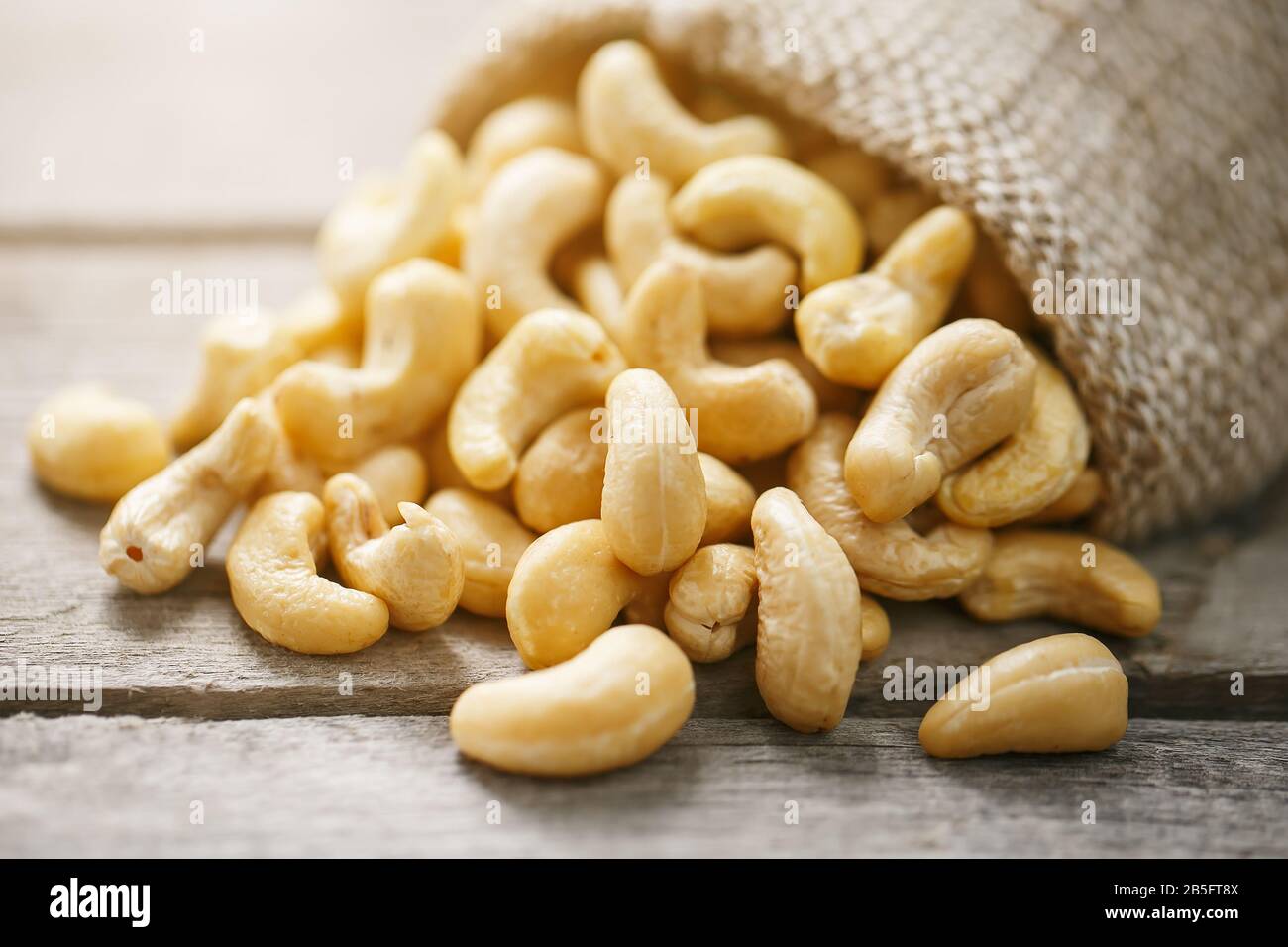 Cashew noci in sacco a sacco su sfondo di legno . Cibo sano. Noce indiano, Anacardio occidentale Foto Stock