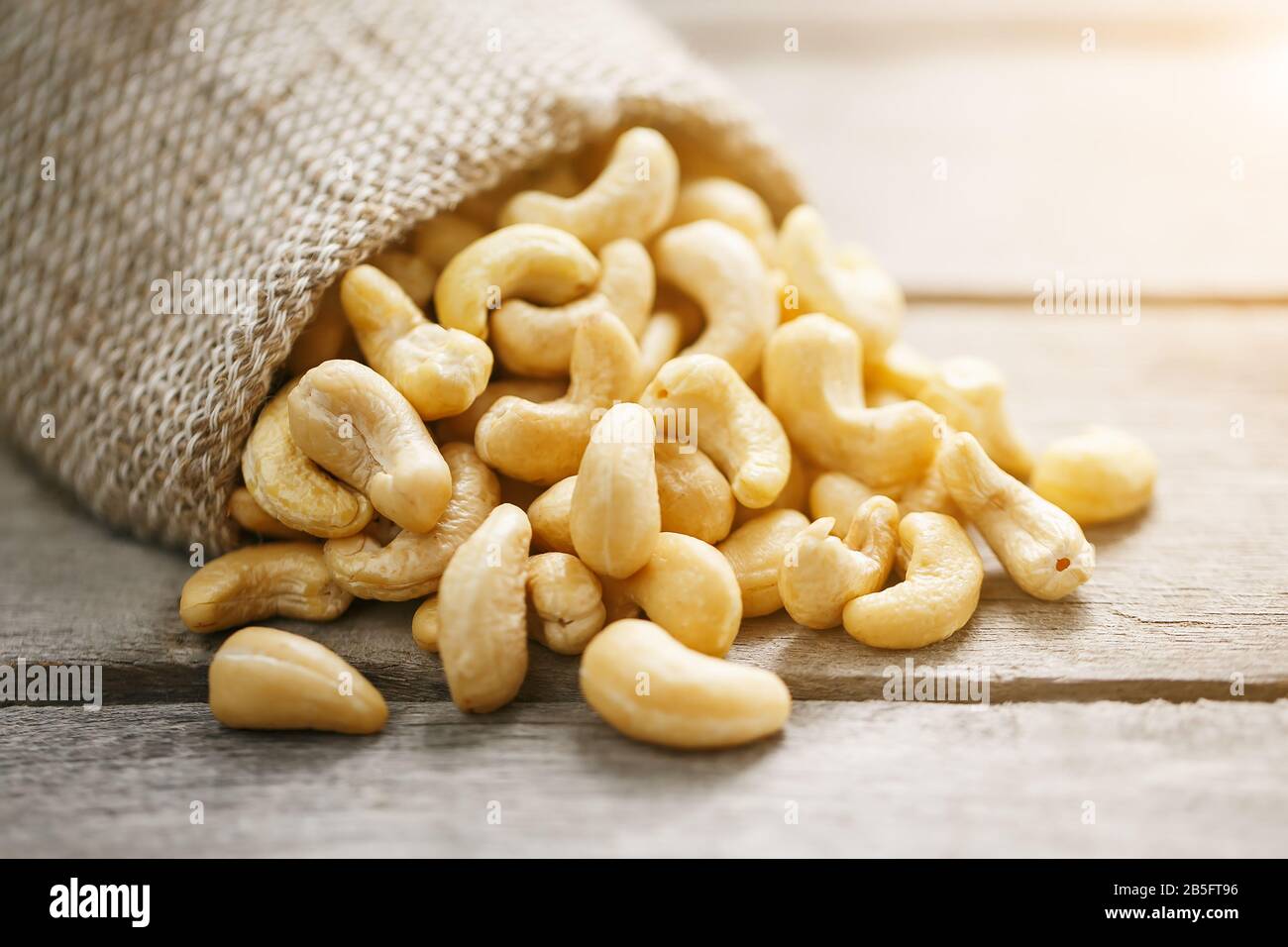 Cashew noci in sacco a sacco su sfondo di legno . Cibo sano. Noce indiano, Anacardio occidentale Foto Stock