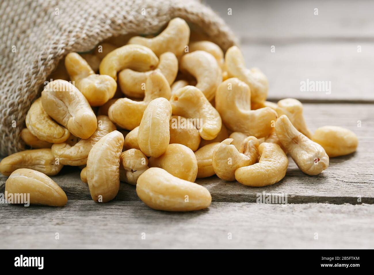 Cashew noci in sacco a sacco su sfondo di legno . Cibo sano. Noce indiano, Anacardio occidentale Foto Stock