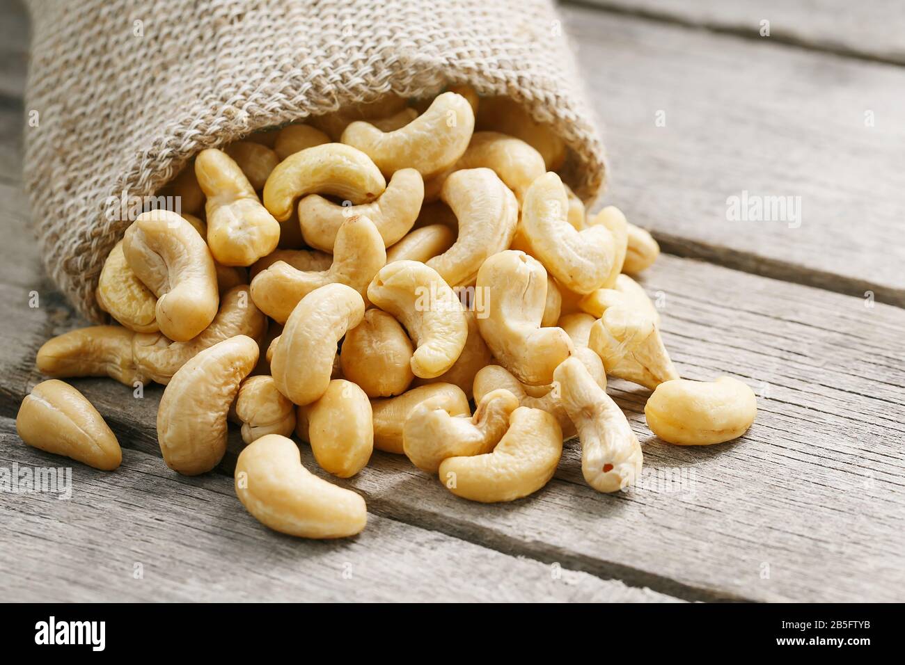 Cashew noci in sacco a sacco su sfondo di legno . Cibo sano. Noce indiano, Anacardio occidentale Foto Stock