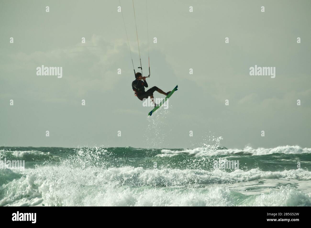 Il kite surfer salta sulle onde e vola attraverso l'aria in mare mosso a Lacanau-Océan, Francia Foto Stock