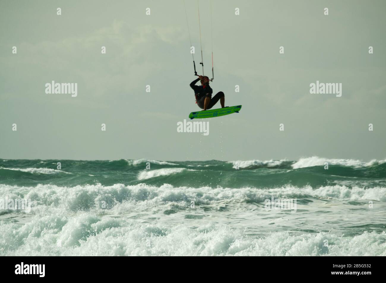 Il kite surfer salta sulle onde e vola attraverso l'aria in mare mosso a Lacanau-Océan, Francia Foto Stock