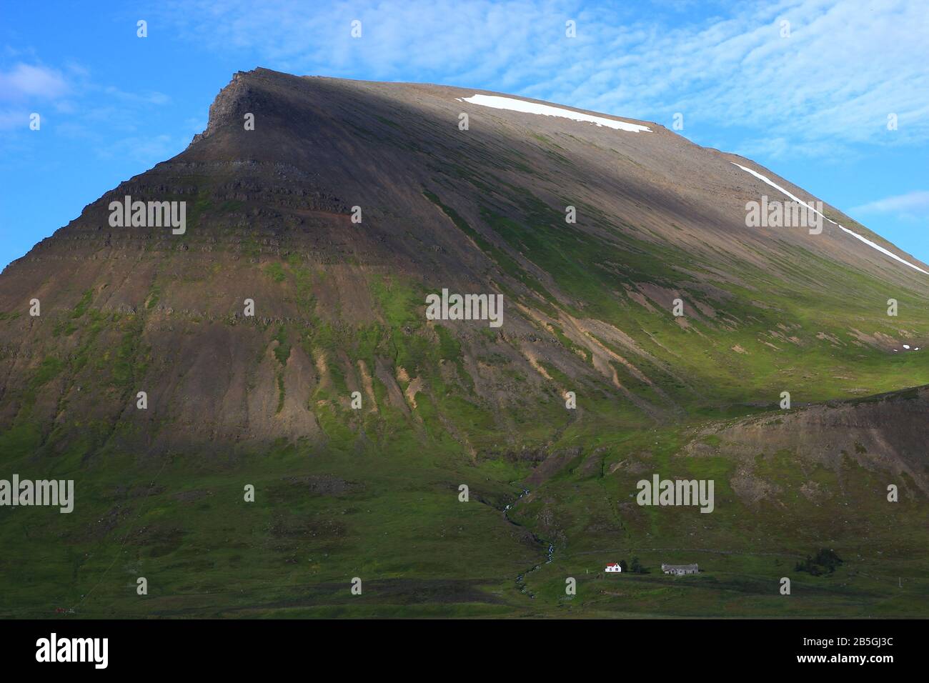 Piccola tipica casa islandese ai piedi di un antico vulcano (luglio vicino al villaggio di Thingeyri, nella regione dei fiordi occidentali) Foto Stock
