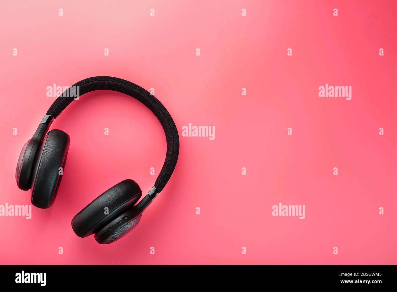 Cuffie wireless nere su sfondo rosa. Cuffie isolate di livello professionale per DJ e musicisti. Vista dall'alto Foto Stock