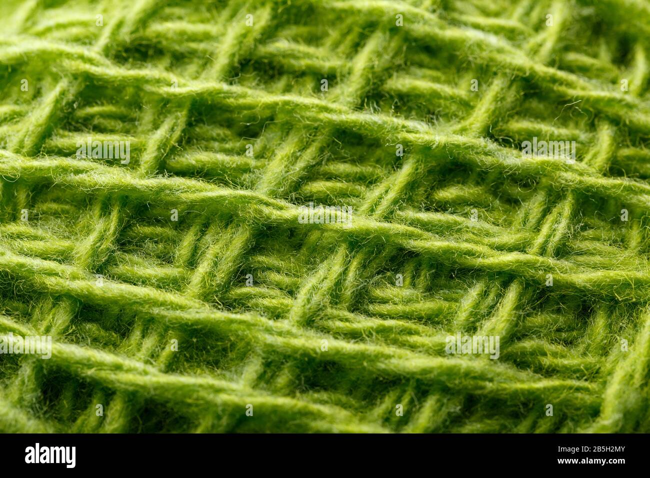 Filo di lana primo piano fili verdi colorati per l'agugliatura in macro. Tessuto di tessitura di fondo per maglia ago. Filato di lana a schermo intero. Foto Stock