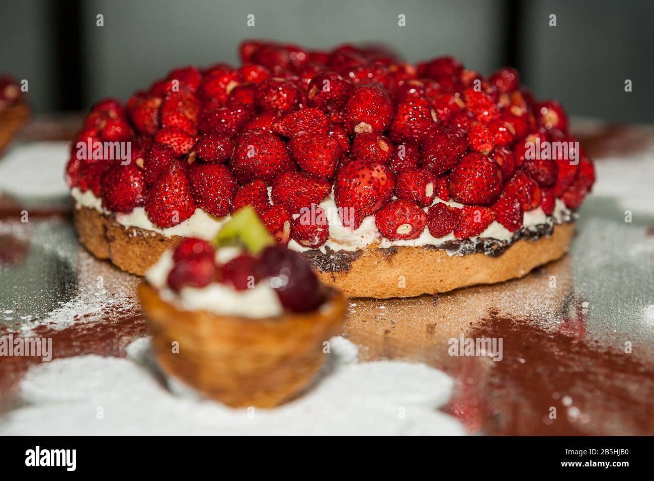 Torta di fragole, torta Di Frutta con crema alla vaniglia, decorazione di zucchero di fiori bianchi. Foto Stock