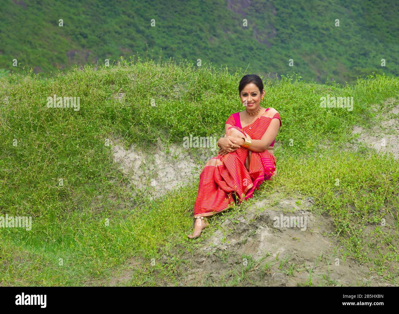 Ritratto di donna attraente sorridente e vestito in abiti tradizionali seduti all'aperto vicino a Guwahati, Assam, India. Foto Stock