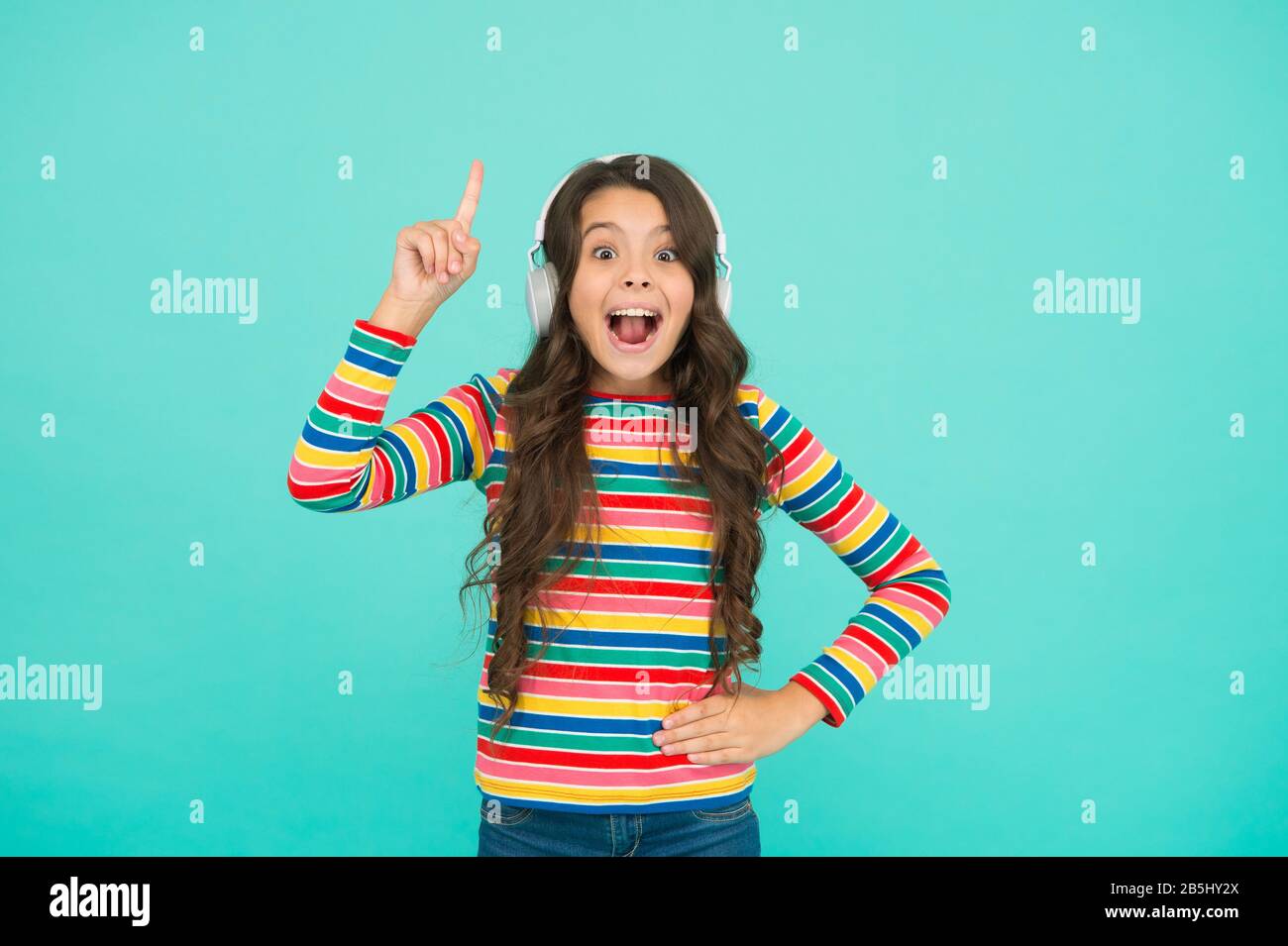 ho avuto un'idea. bambina ascolta musica in cuffia. audio libro letteratura per bambini. teen kid esprimere positività. studentessa ottimista indossa abiti colorati. ispirata alla canzone. su tono positivo. Foto Stock