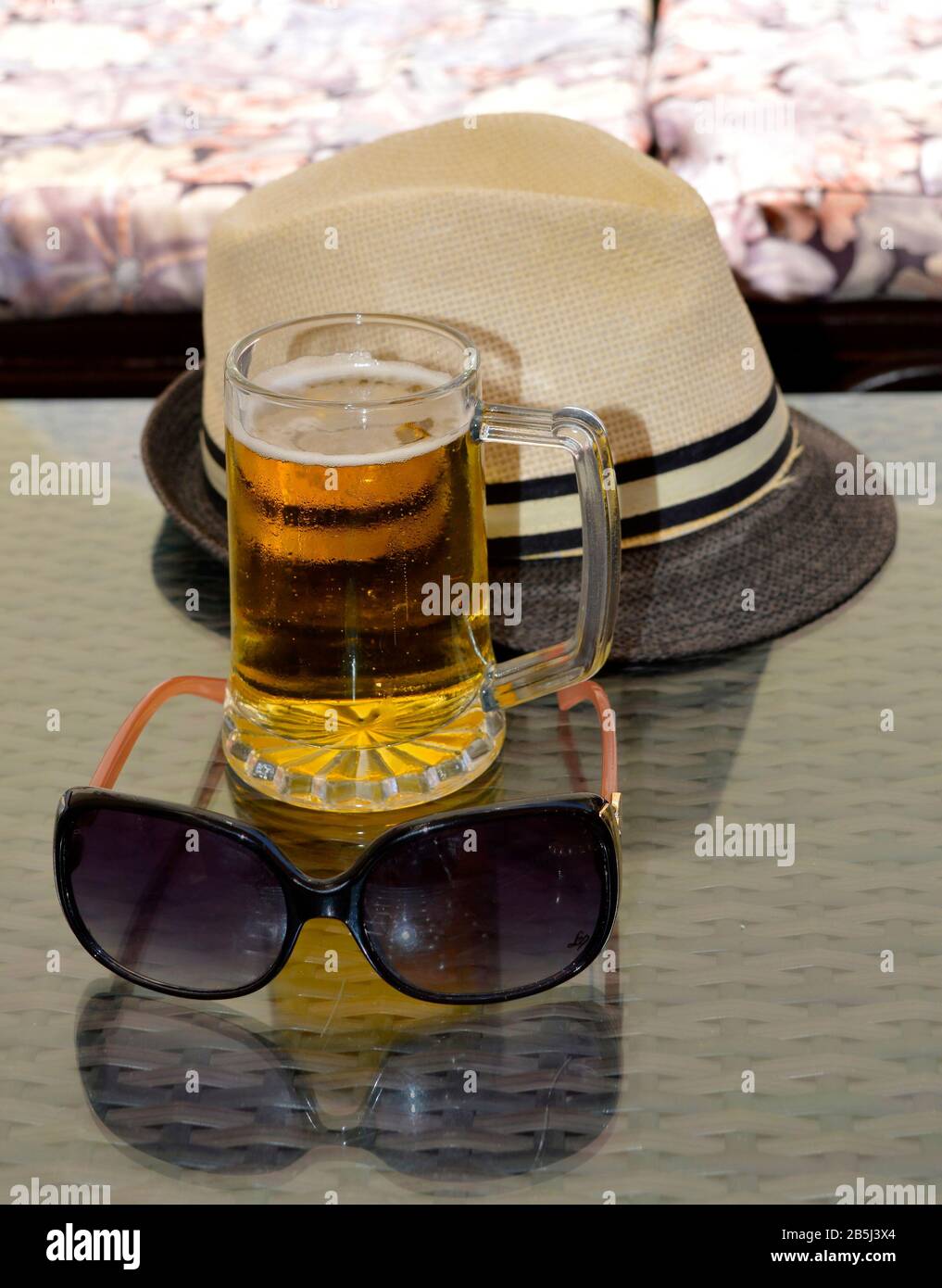 Gli indispensabili per le vacanze sono un cappello e occhiali da sole per un po' di ombra e una grande birra per rinfrescarsi Foto Stock