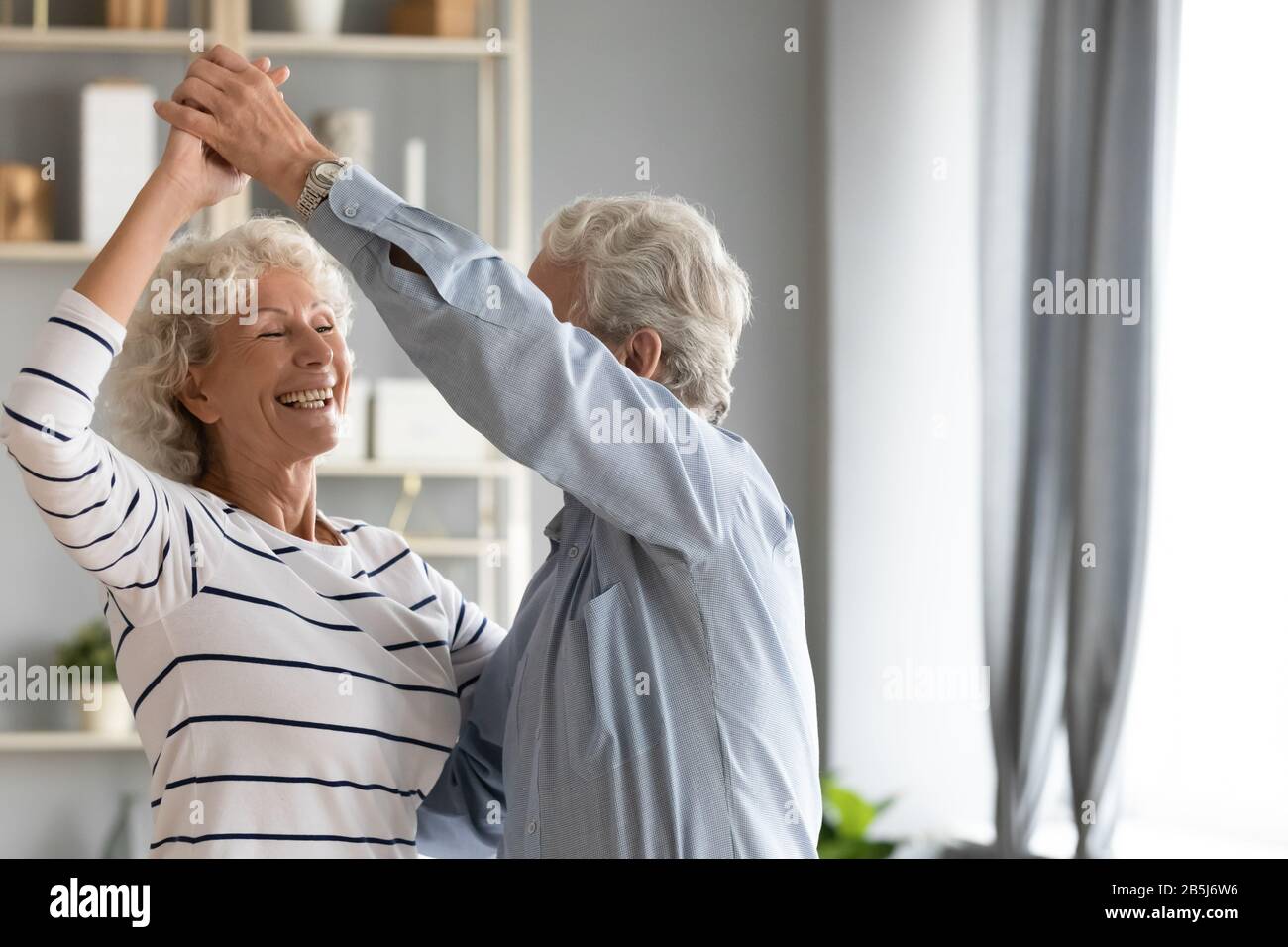 Il marito maturo e la moglie sono pieni di gioia e danzano nel soggiorno Foto Stock