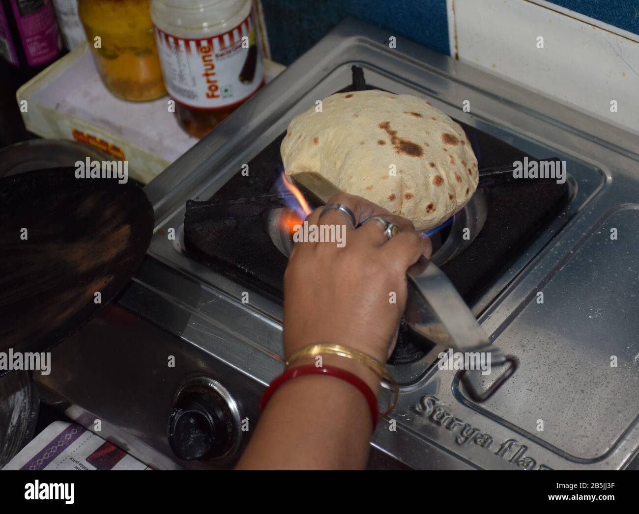 Una donna che fa chapati o Roti nel suo bruciatore a gas. Cucina indiana, cucina indiana, piatti indiani Foto Stock