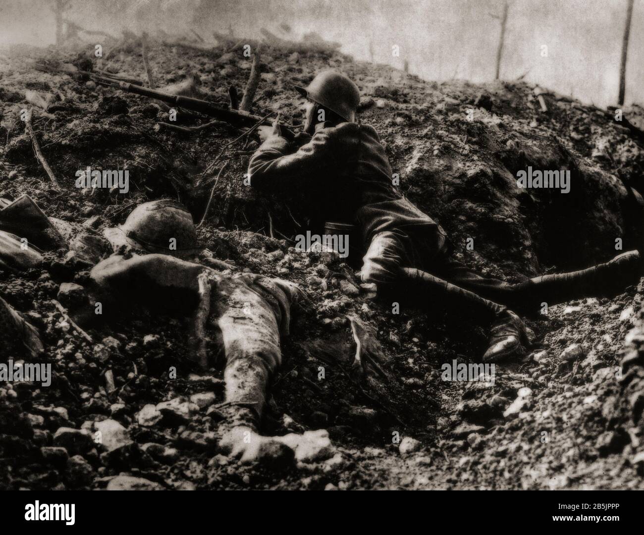 Durante la battaglia di Verdun nel febbraio 1916, un soldato tedesco che usa la copertura di una trincea danneggiata accanto al corpo di un soldato francese. Foto Stock