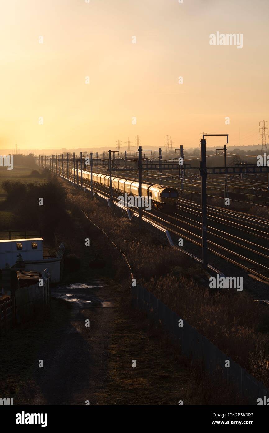 DB cargo classe 66 locomotiva diesel con un treno merci a Coedkernew sulla linea principale del Galles meridionale che si incagliano al tramonto Foto Stock