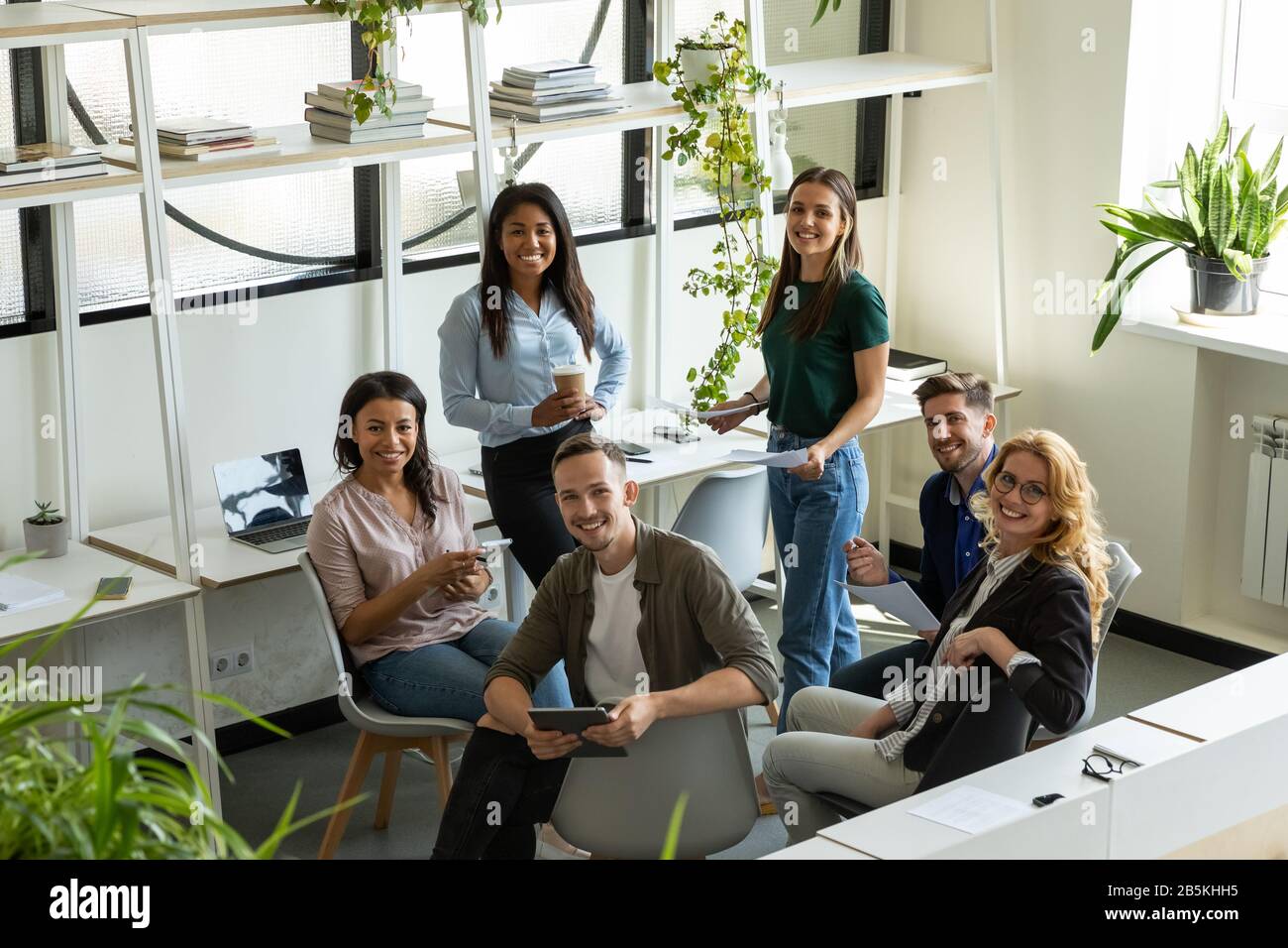 I colleghi più numerosi e felici discutono delle idee durante il briefing Foto Stock