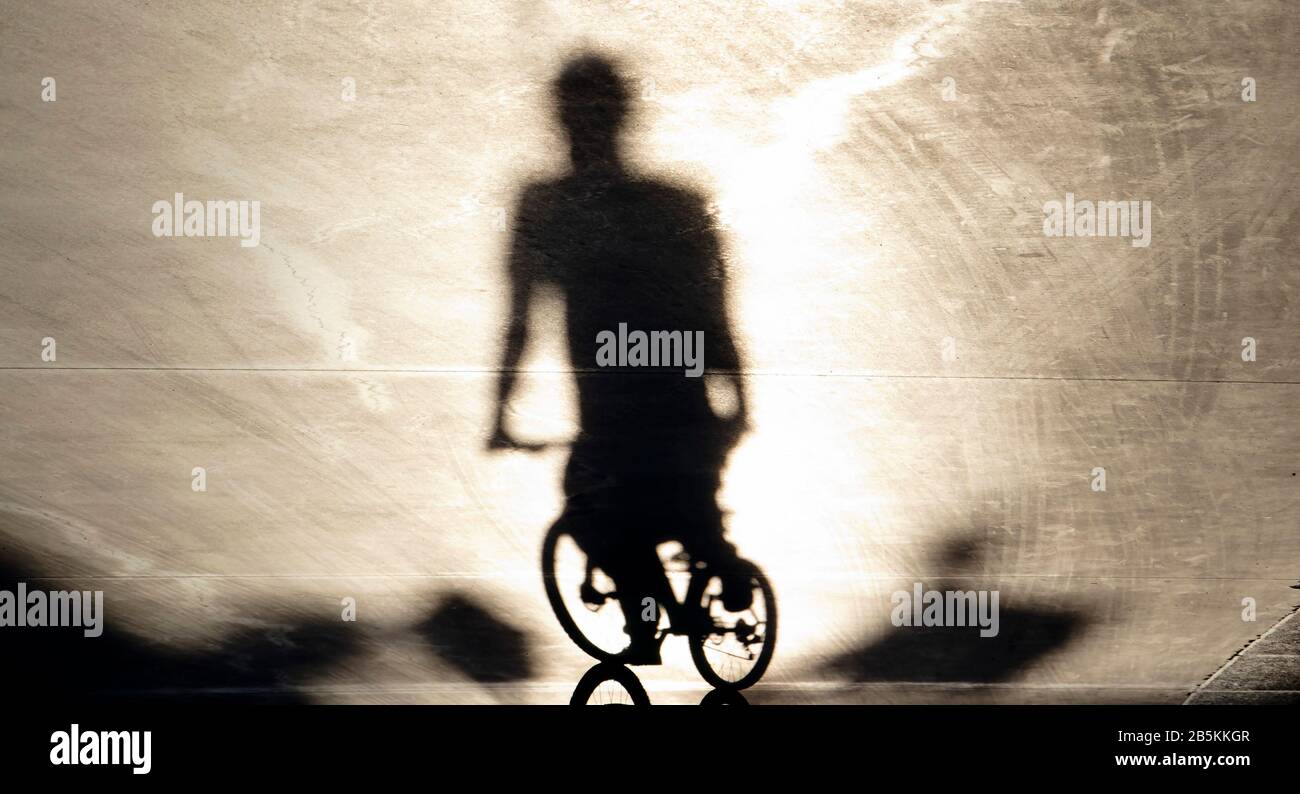 Ombra sfuocata di un giovane uomo in bicicletta al tramonto d'estate Foto Stock